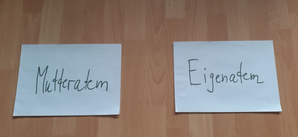 Zwei Zettel mit den Aufschriften Mutteratem und Eigenatem, in etwas Abstand auf dem Boden